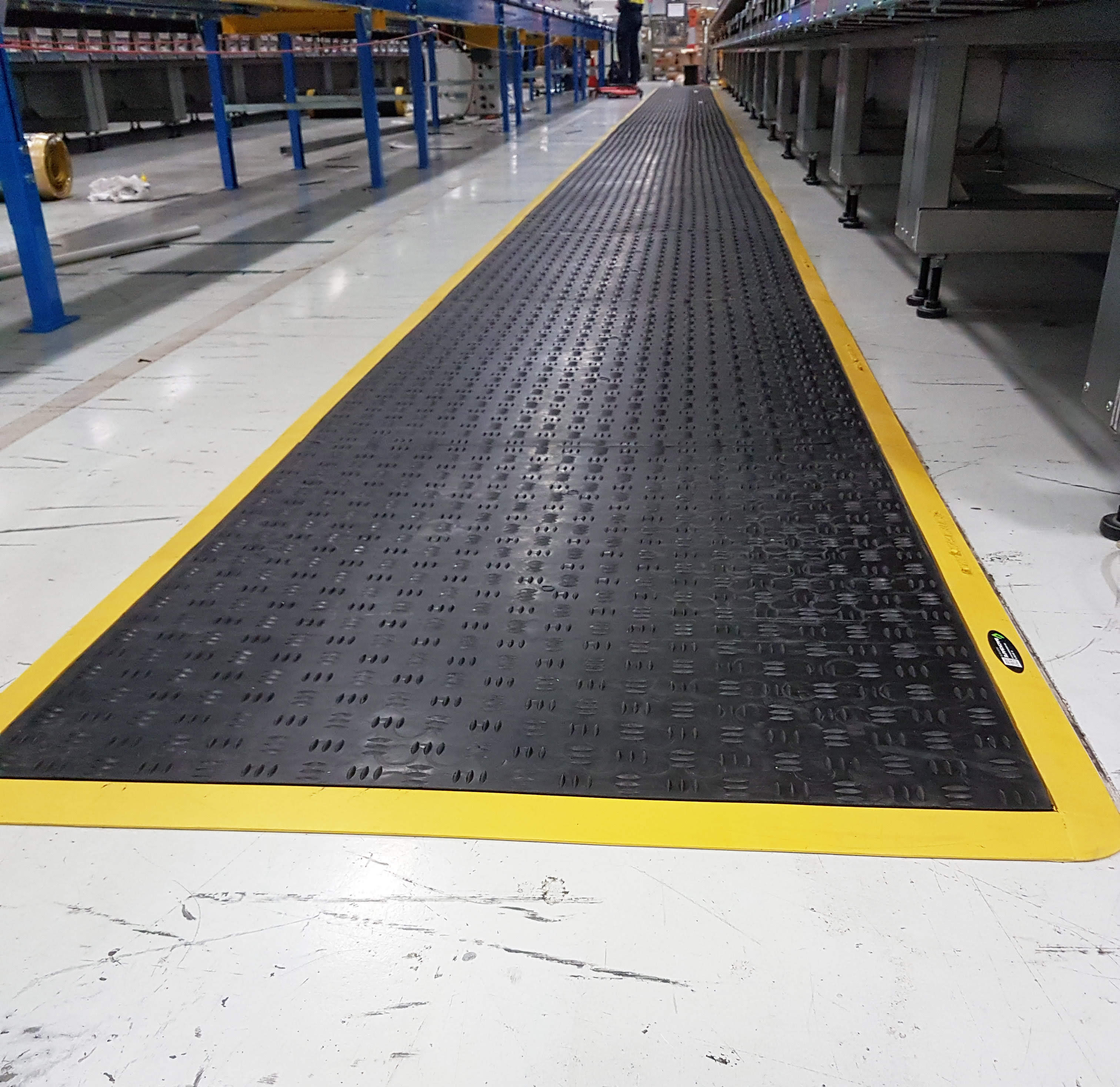 Safety matting placed next to automated rollers and workstations in an Australia Post distribution center.
